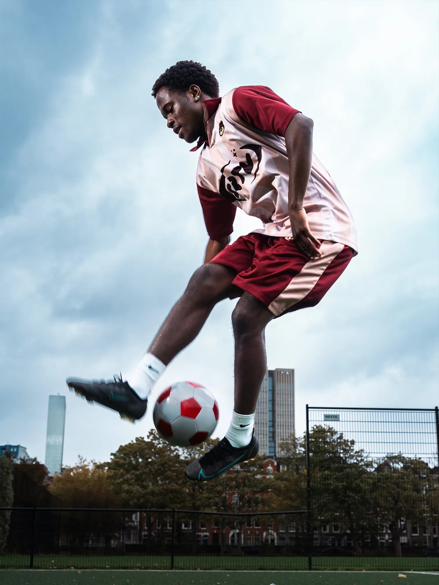 Person playing soccer on a field with buildings in the background
