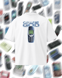 A white short-sleeve t-shirt featuring a graphic print of a classic blue Nokia mobile phone with the text 'CALLING GOD' above it. The t-shirt is centered against a blurred background composed of numerous floating vintage mobile phones.