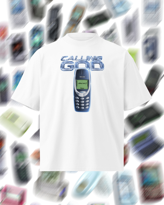 A white short-sleeve t-shirt featuring a graphic print of a classic blue Nokia mobile phone with the text 'CALLING GOD' above it. The t-shirt is centered against a blurred background composed of numerous floating vintage mobile phones.